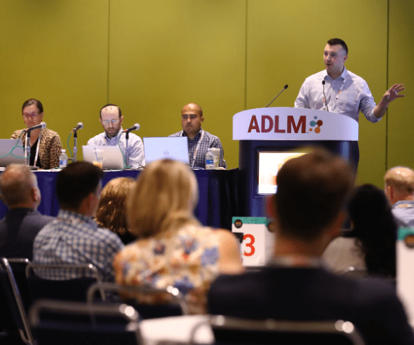 A panel of speakers in front of an audience at ADLM University