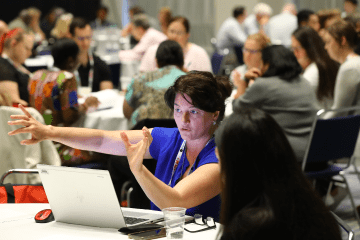 Conference attendees with laptops at roundtable conference sessions
